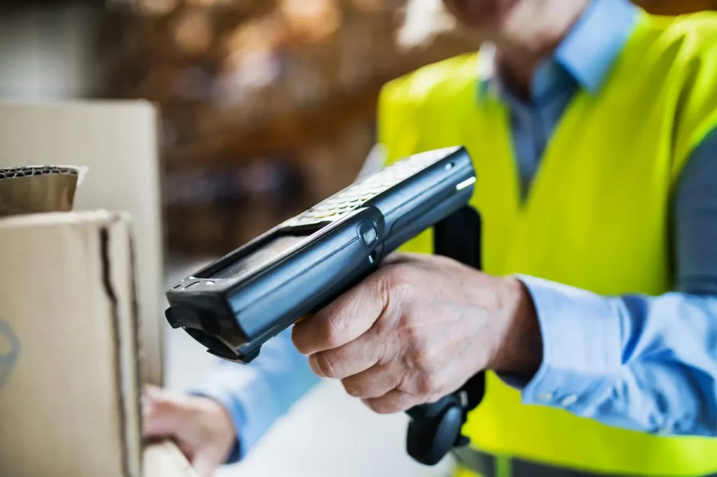 Travailleur logistique scannant un colis à transférer sur un quai de chargement