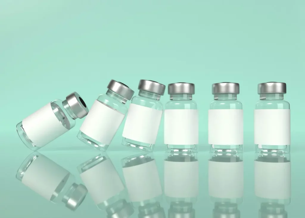 Rangée de fioles pharmaceutiques en verre à capsule argentée sur fond menthe